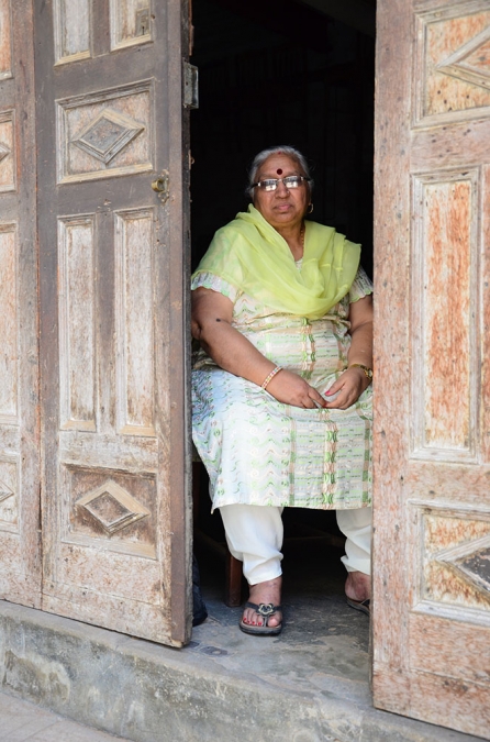Eşinin marangoz atölyesinin kapısında oturan Hintli bir bayan